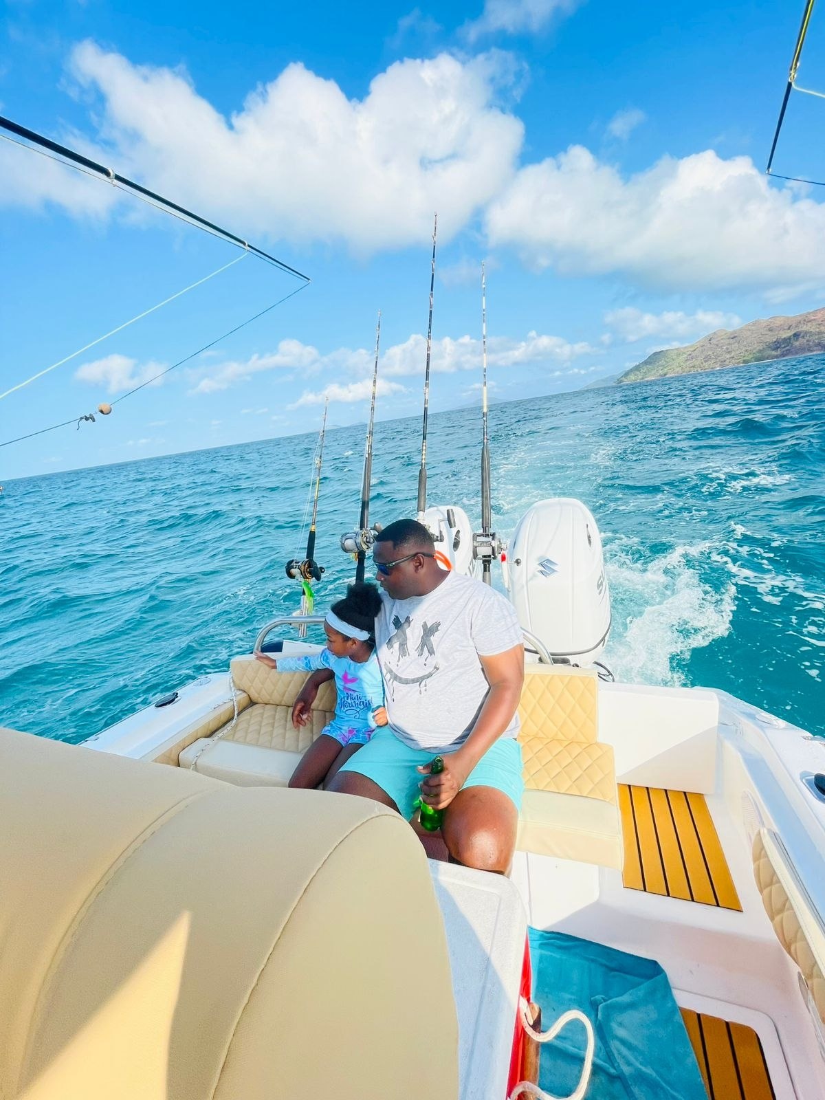 A guest and a child seated at the stern with fishing rods in the holders