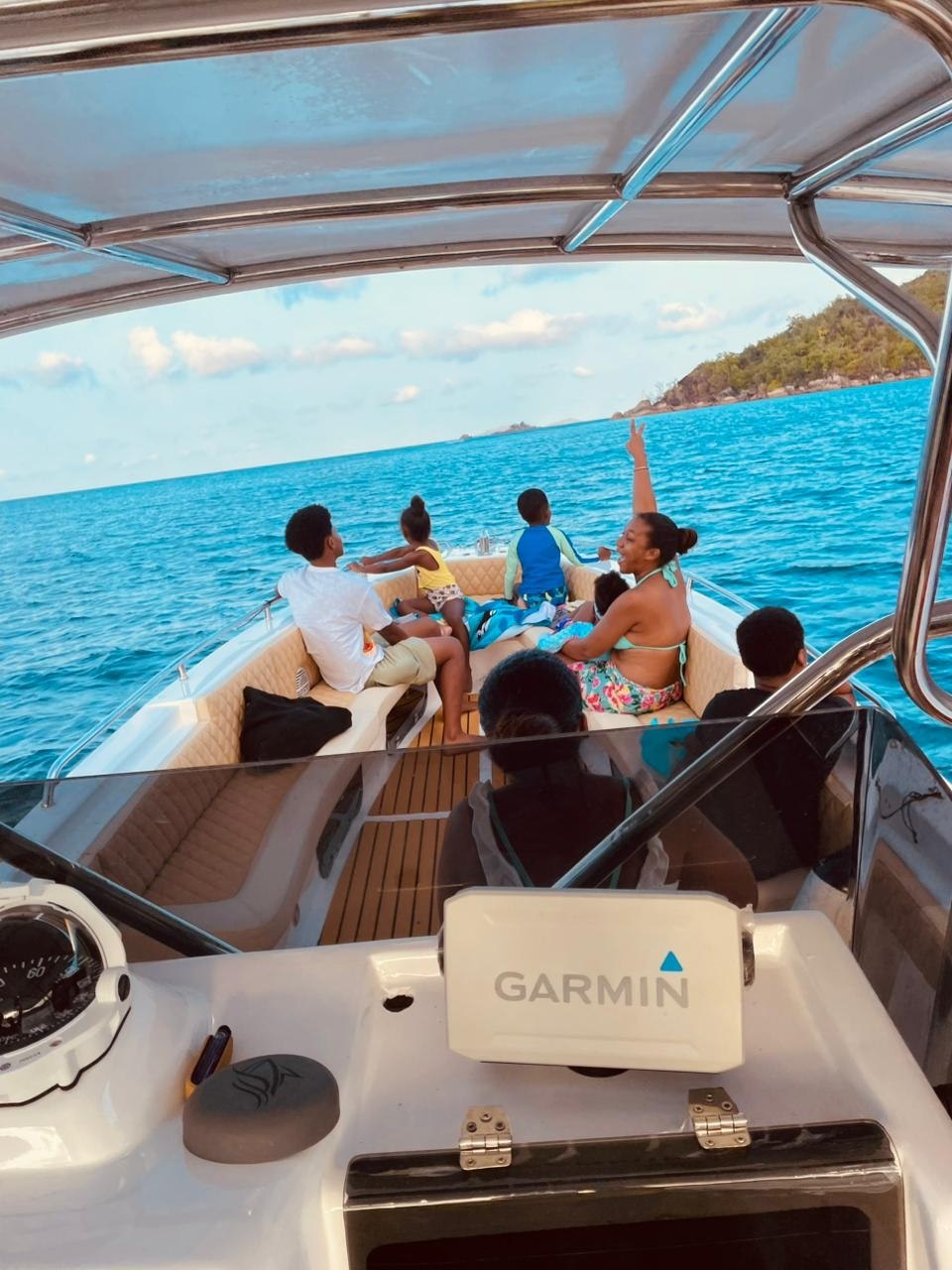 Guests seated in the bow of the charter boat looking out over blue water towards an island